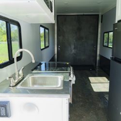 Interior of a Stealth Nomad toy hauler with garage space, living area, kitchen, and rubberized flooring.